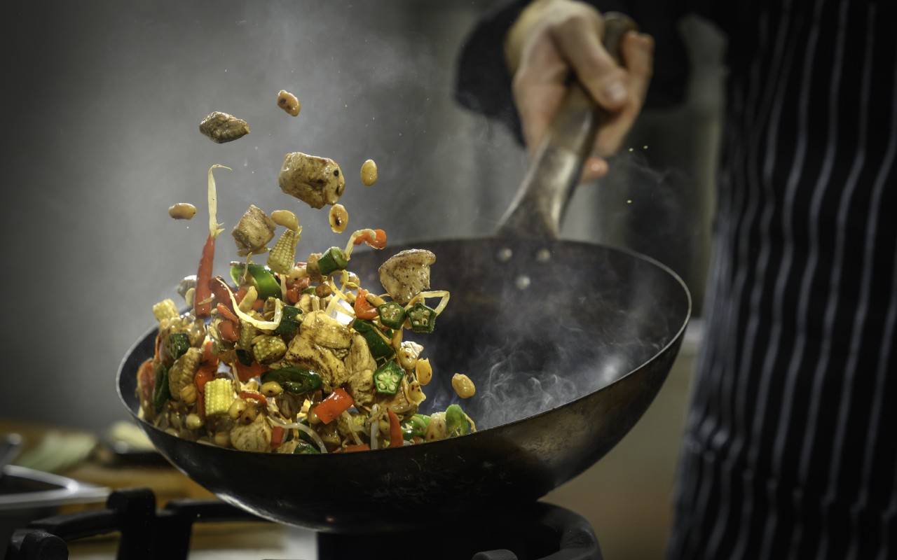 Stir-frying vegetables and meat in wok.
