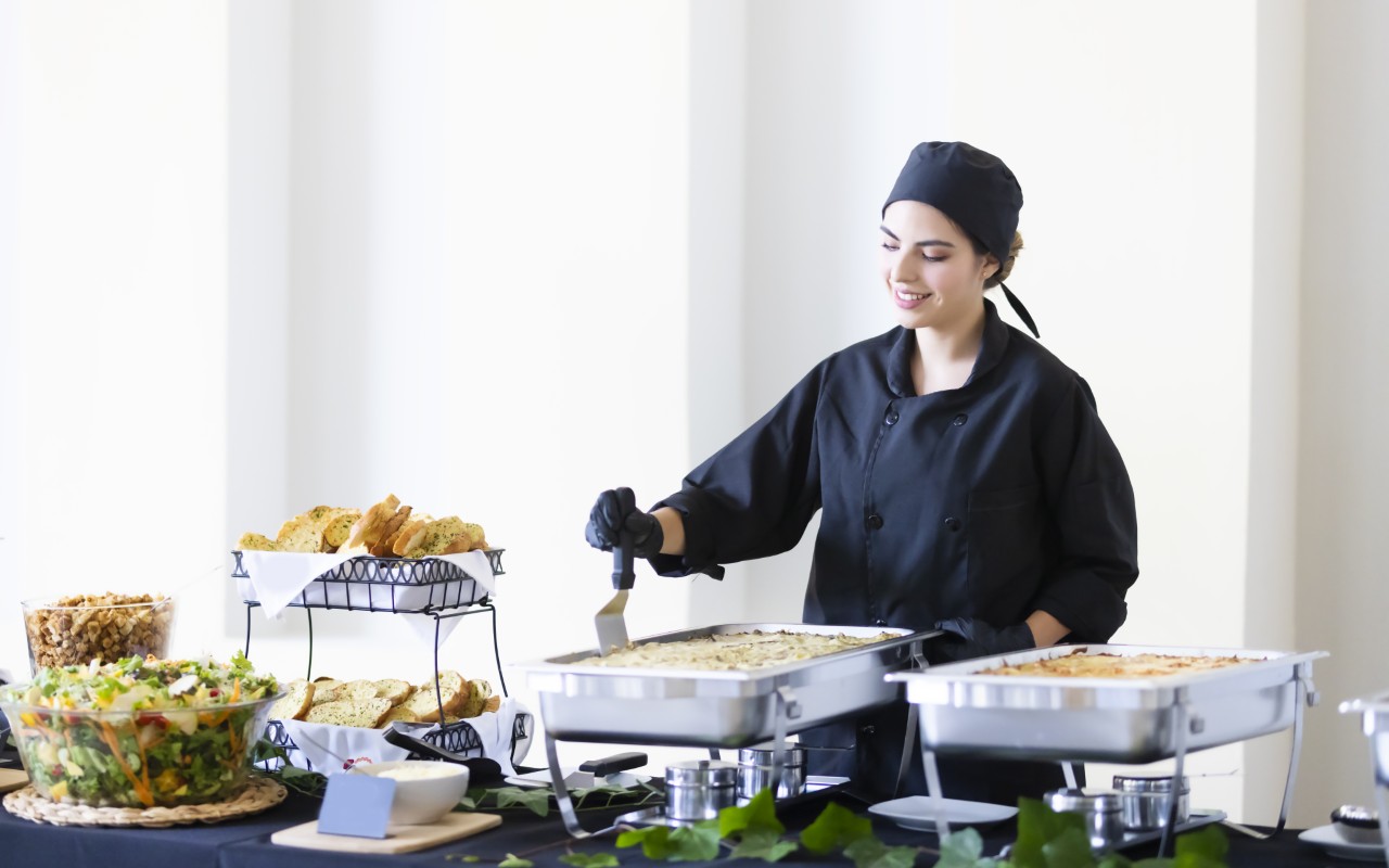Chef serving food at a buffet table.