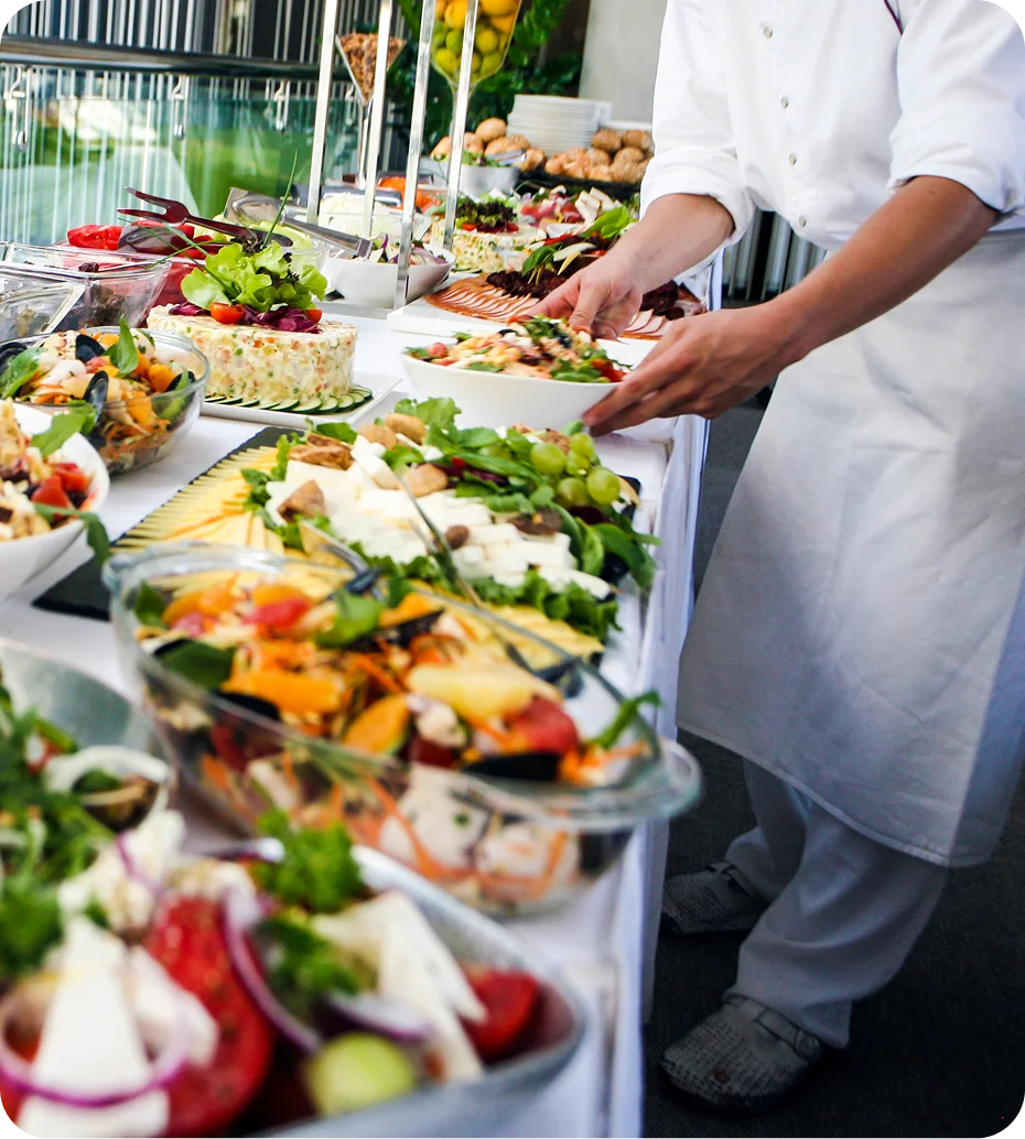 Chef arranging colorful buffet table with salads.
