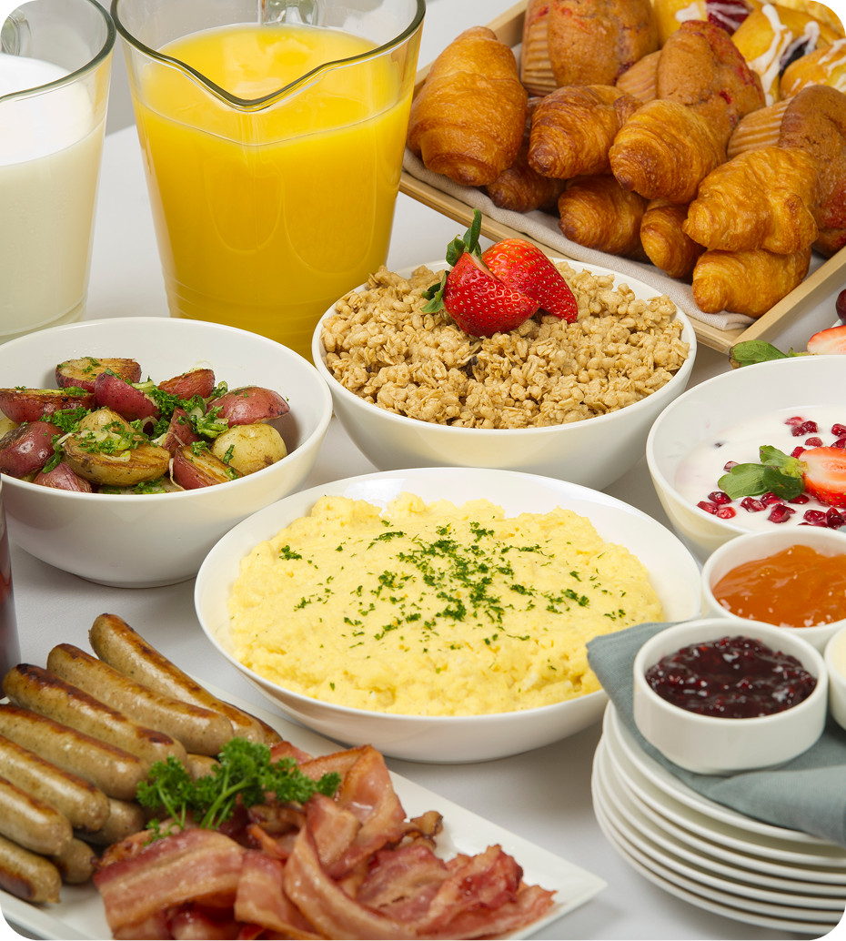 Breakfast spread with croissants, sausages, and juice.