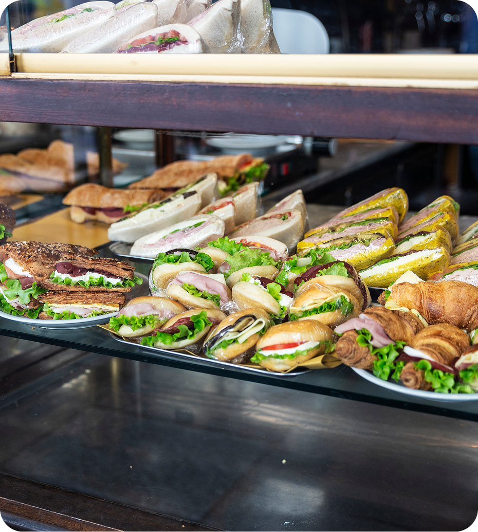 Assorted sandwiches displayed in a bakery case.