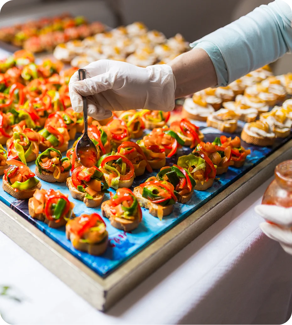 Hand arranging colorful appetizers on platter.