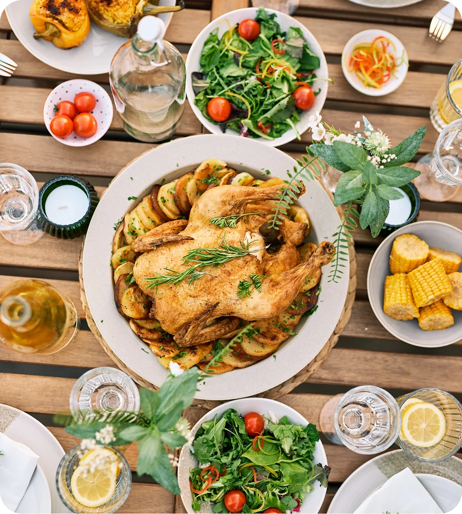 Roast chicken with vegetables on wooden table.