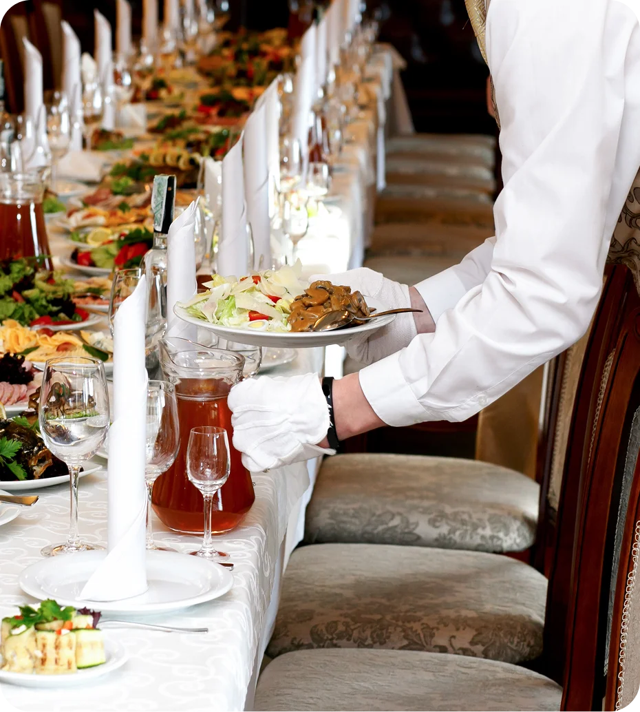 Waiter serving food at elegant banquet table.