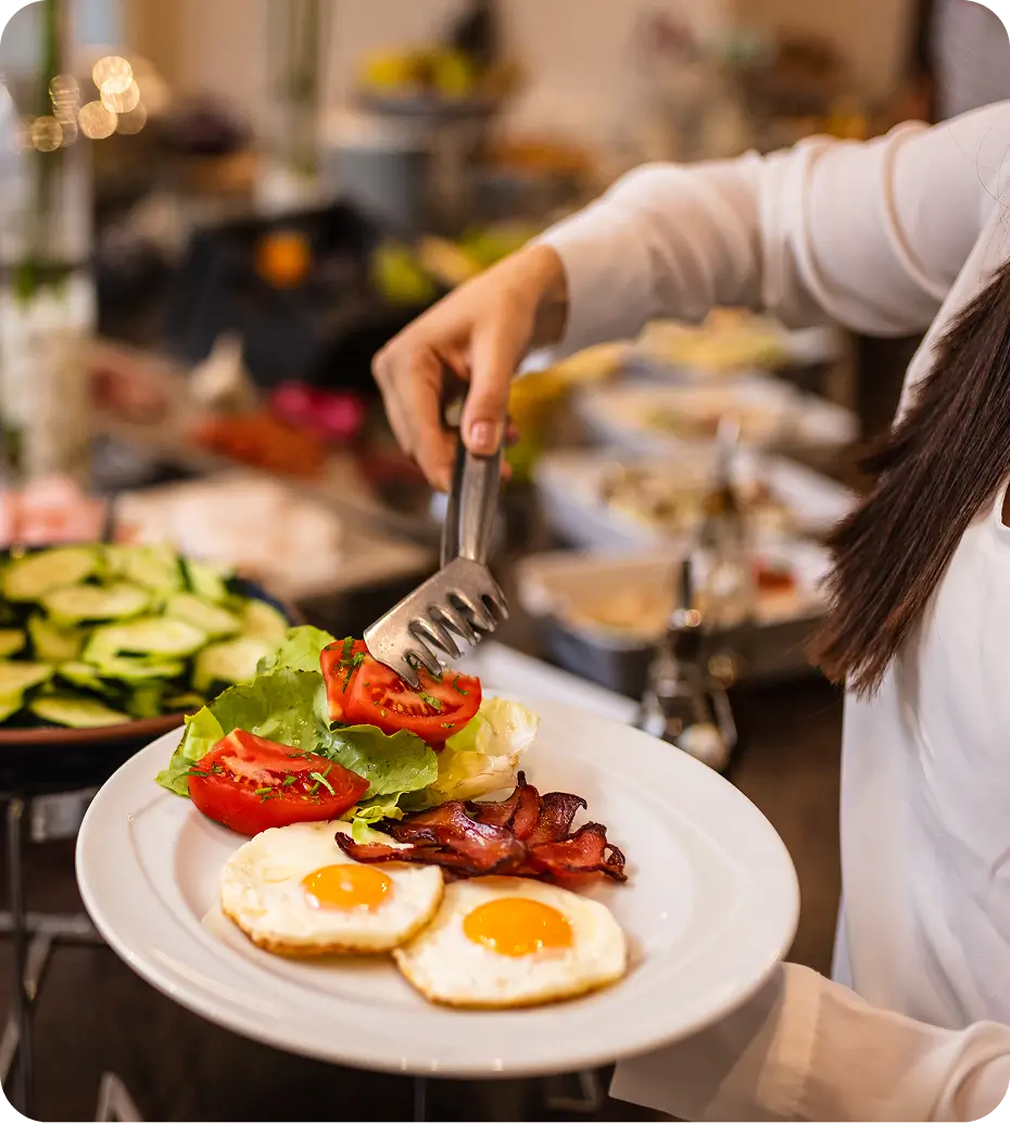 Person serving salad and eggs at buffet.