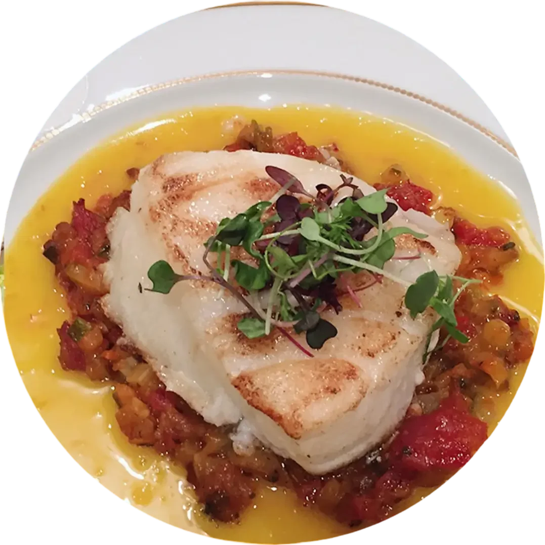 Grilled fish with vegetables and microgreens garnish.